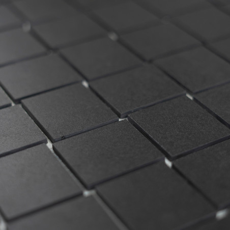 Les carreaux carrés sombres sont disposés selon un motif en grille, créant une surface uniforme et minimaliste qui suggère un re