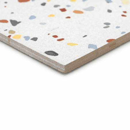 Een terrazzotegel ligt plat en vertoont kleurrijke, onregelmatige steenfragmenten op een lichtgrijs oppervlak, met een gladde, a Een terrazzotegel ligt plat en vertoont kleurrijke, onregelmatige steenfragmenten op een lichtgrijs oppervlak, met een gladde, a