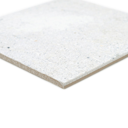 Um ladrilho cerâmico liso e quadrado repousa sobre um fundo branco, mostrando uma superfície manchada de cinza claro e bege.