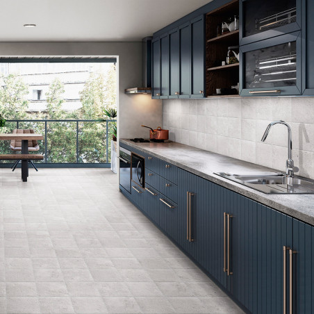 Uma cozinha moderna apresenta armários azuis com puxadores elegantes, backsplash de azulejos cinza e bancada de pedra. A luz sol