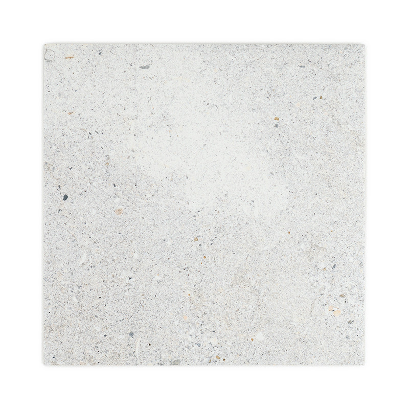 O objeto é um ladrilho de pedra quadrado, com superfície salpicada e texturizada em tons de cinza e bege, sobre um fundo branco.