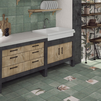 La encimera de la cocina cuenta con cajones de madera y un fregadero grande, rodeado de azulejos de color verde terroso con moti