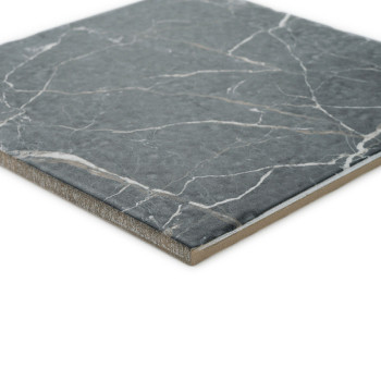 Un carreau carré présente une surface marbrée grise avec des motifs veinés blancs, sur un fond blanc uni.