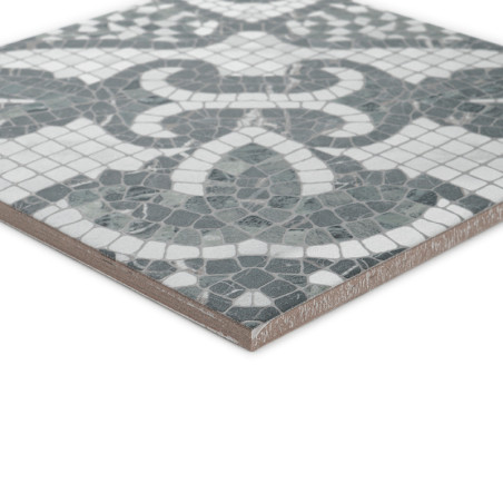 The square tile features a mosaic pattern of interlocking green and white shapes, resting on a smooth, light brown edge.