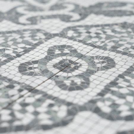 Les carreaux de mosaïque gris et blancs forment des motifs géométriques complexes, mettant en valeur des formes circulaires et e