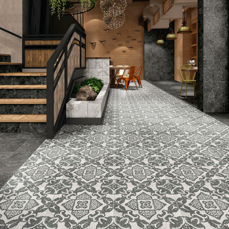 Intricate patterned tiles cover the floor, leading to a dining area in a warmly lit, modern interior with stairs and plants.