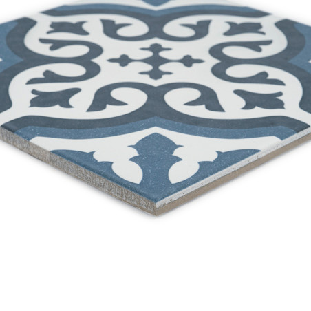 Le carreau présente un motif floral orné en bleu foncé et blanc, présentant des courbes symétriques et des feuilles stylisées su Le carreau présente un motif floral orné en bleu foncé et blanc, présentant des courbes symétriques et des feuilles stylisées su