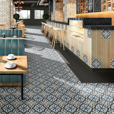 Des carreaux ornés à motifs bleus et blancs recouvrent le sol d'un café, s'étendant jusqu'à un comptoir en bois avec des taboure Des carreaux ornés à motifs bleus et blancs recouvrent le sol d'un café, s'étendant jusqu'à un comptoir en bois avec des taboure