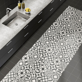Ladrilhos geométricos preto e branco cobrem uma seção do chão da cozinha ao lado de uma bancada cinza moderna com pia e garrafas