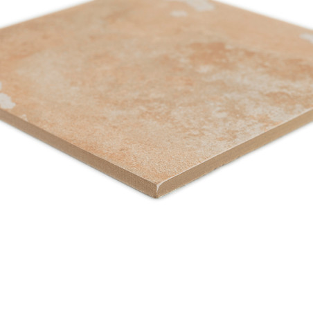 A square, beige ceramic tile with a slightly textured surface rests on a white background, highlighting its smooth edges.