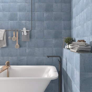 Keramikfliesen bedecken die Badezimmerwände und sorgen für eine beruhigende blaue Atmosphäre. Eine Badewanne, Regale mit gefalte