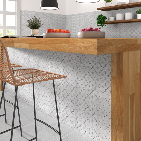 A wooden kitchen counter with stools stands against a patterned tile wall, surrounded by shelves holding plants and bowls of fru A wooden kitchen counter with stools stands against a patterned tile wall, surrounded by shelves holding plants and bowls of fru