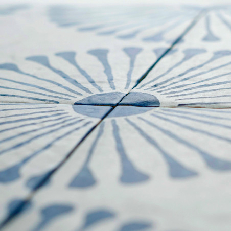 Die Keramikfliese weist ein radiales Blumenmuster mit blauen, blütenblattähnlichen Formen auf, die von einem zentralen Kreis aus