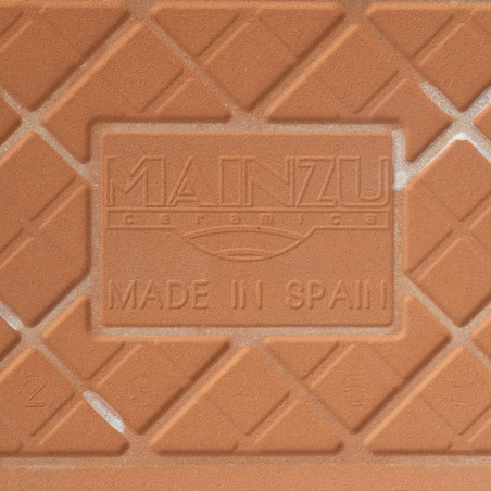 Een keramische tegel van terracotta heeft verhoogde ruitpatronen en de tekst in reliëf met de tekst `MAINZU Ceramica` en `MADE I