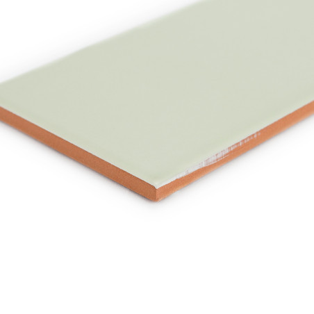 Un carreau rectangulaire avec une surface lisse et vert pâle est représenté à plat, avec ses bords brun orangé visibles, dans un Un carreau rectangulaire avec une surface lisse et vert pâle est représenté à plat, avec ses bords brun orangé visibles, dans un
