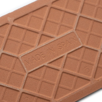 O ladrilho de terracota exibe um padrão de grade com uma etiqueta em relevo que diz “MADE IN SPAIN”, destacando o artesanato e a