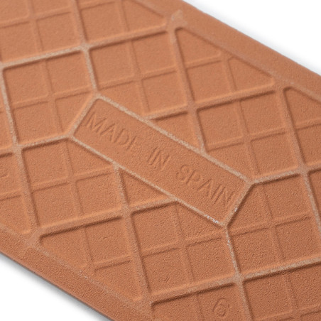 Un carreau en terre cuite présente un motif de grille avec le texte en relief indiquant « MADE IN SPAIN », sur une surface de fo