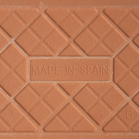 Un carreau en terre cuite comporte le texte en relief « MADE IN SPAIN » entouré d'un motif géométrique de lignes diagonales qui Un carreau en terre cuite comporte le texte en relief « MADE IN SPAIN » entouré d'un motif géométrique de lignes diagonales qui