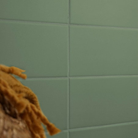 Una cuadrícula de azulejos rectangulares verdes forma una pared lisa, parcialmente oscurecida por la textura desenfocada de fibr Una cuadrícula de azulejos rectangulares verdes forma una pared lisa, parcialmente oscurecida por la textura desenfocada de fibr