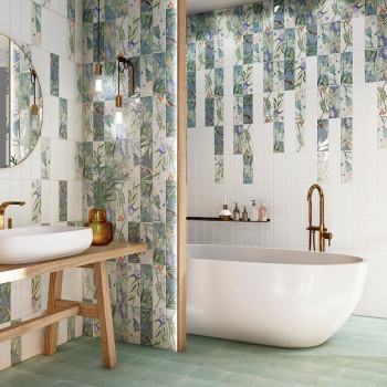 Uma banheira branca fica sob uma parede adornada com azulejos com motivos florais e faixas verticais de espelhos. Uma pia de mad