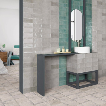 Een moderne badkamer met grijze en blauwgroen wandtegels is voorzien van een strakke metalen wastafel met spiegel in een minimal