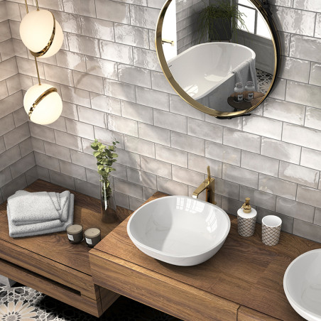 Op een houten wastafel staat een witte wastafel, vergezeld van toiletartikelen en handdoeken. Een ronde spiegel weerspiegelt een