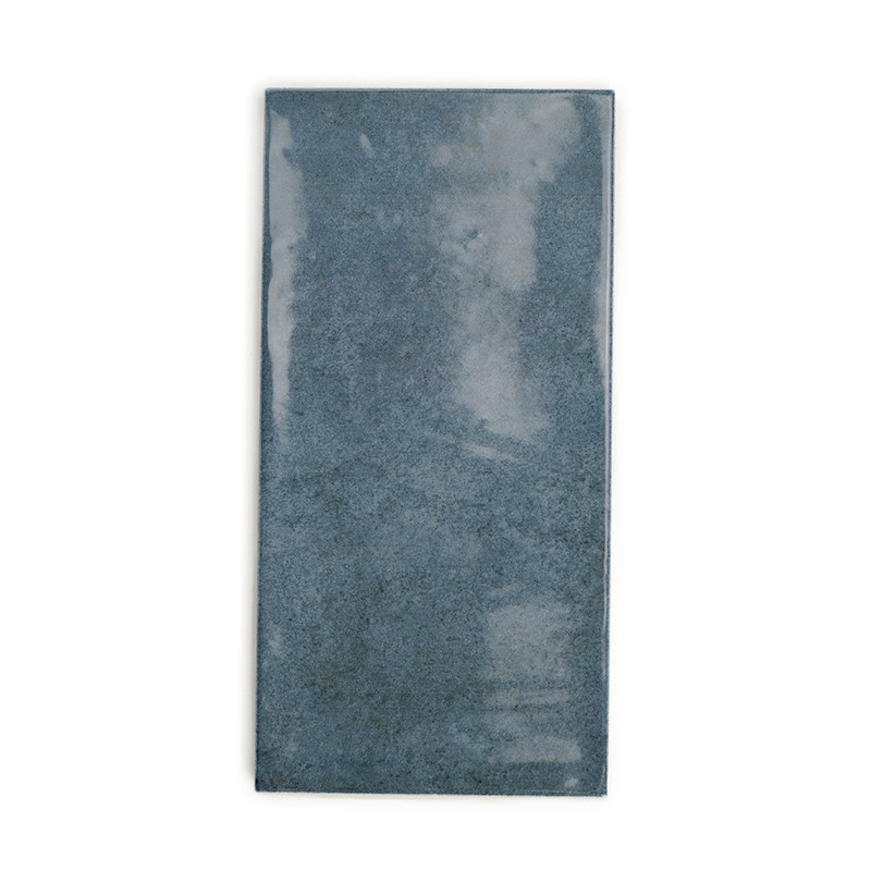 Carreau de céramique rectangulaire, présentant une surface bleu-gris brillante et trouble. apparaît sur un fond blanc uni.