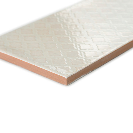 Un carreau de céramique rectangulaire repose en diagonale et présente une surface brillante à motif de losanges. Ses bords révèl