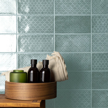 Los azulejos turquesas presentan intrincados patrones geométricos y festoneados. Una bandeja de madera contiene botellas y un pa