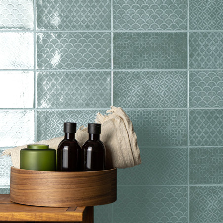 Los azulejos turquesas presentan intrincados patrones geométricos y festoneados. Una bandeja de madera contiene botellas y un pa Los azulejos turquesas presentan intrincados patrones geométricos y festoneados. Una bandeja de madera contiene botellas y un pa