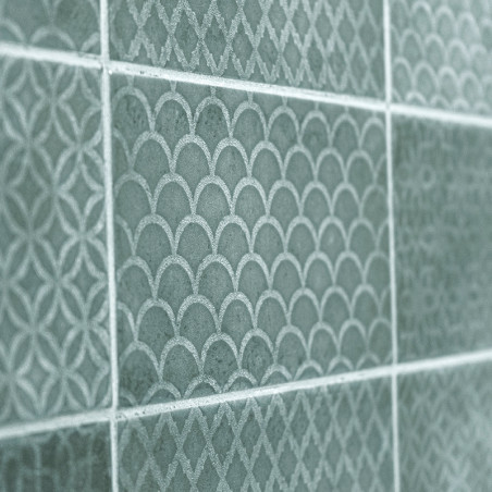 Les carreaux de céramique verte affichent des motifs complexes et répétitifs d’arcs et de losanges, créant une surface murale te Les carreaux de céramique verte affichent des motifs complexes et répétitifs d’arcs et de losanges, créant une surface murale te