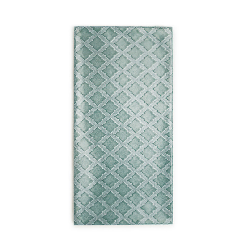 Un carreau rectangulaire affiche un motif géométrique de diamants entrelacés dans diverses nuances de sarcelle, sur un fond blan