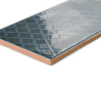 Un carreau de céramique rectangulaire présente une surface bleu foncé brillante avec un motif géométrique subtil, placé sur un f