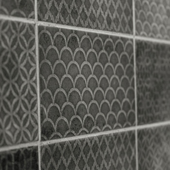 Uma série de azulejos escuros texturizados apresenta padrões geométricos, incluindo escalas e desenhos de treliça, formando uma 