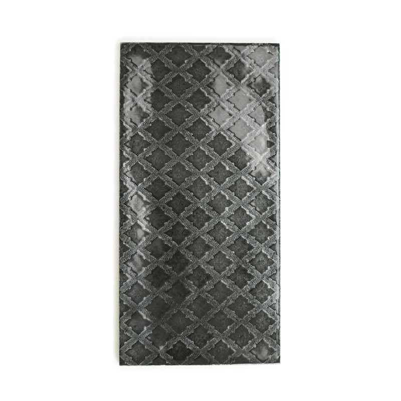 El azulejo rectangular presenta una superficie brillante de color gris oscuro con un patrón geométrico repetitivo de diamantes. 