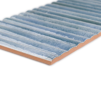 O ladrilho retangular apresenta relevo estriado, em tons de azul e branco, colocado sobre fundo marrom, criando uma superfície t