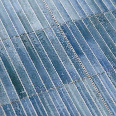 Les carreaux rectangulaires bleus se chevauchent, créant une surface texturée. De subtiles variations de couleurs et de brillanc