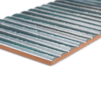 Un carreau de céramique rectangulaire présente des crêtes horizontales surélevées dans un vernis bleu brillant, posées sur un bo