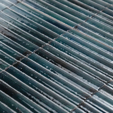 Rectangular, glossy tiles are arranged in parallel rows, displaying a gradient of dark green and blue shades, reflecting light s