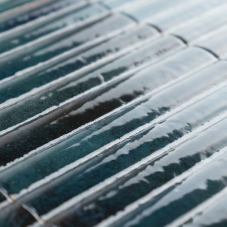 Ceramic tiles, glazed with a glossy, blue-green finish, lie in a staggered arrangement, creating a textured, wavy surface patter