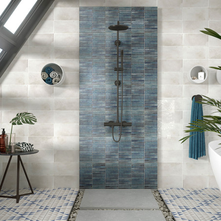 Une pomme de douche centrale sombre montée sur des carreaux verticaux à rayures bleues se trouve au milieu de carreaux muraux be Une pomme de douche centrale sombre montée sur des carreaux verticaux à rayures bleues se trouve au milieu de carreaux muraux be