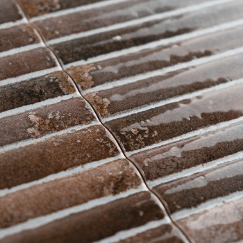 Les carreaux de céramique marron affichent une texture brillante et nervurée, alignée en parallèle avec de légères variations de
