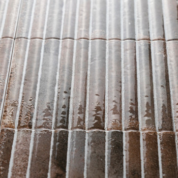 Les carreaux de céramique bruns brillants avec des crêtes verticales réfléchissent la lumière et semblent humides. Ils sont disp