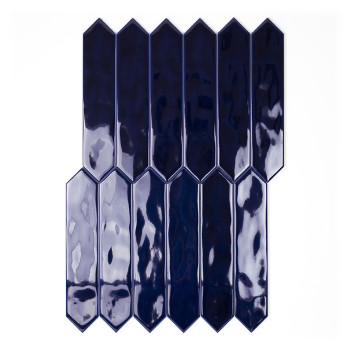 Un carreau bleu foncé brillant aux extrémités pointues se trouve verticalement sur un fond blanc uni, réfléchissant la lumière s