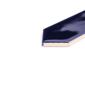 Un carreau de céramique bleu foncé brillant présente un bord biseauté sur un fond blanc, soulignant sa surface polie et son épai