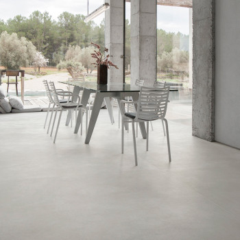 Een set witte stoelen omringt een moderne eettafel binnenshuis, met grote ramen die uitzicht bieden op een sereen buitenlandscha