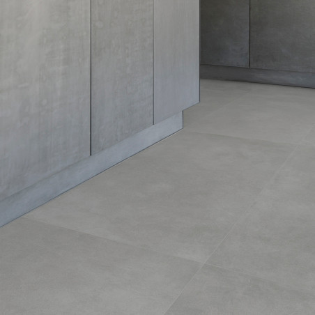 Grandes azulejos grises lisos forman un piso debajo de gabinetes minimalistas de color gris claro, creando un ambiente de cocina