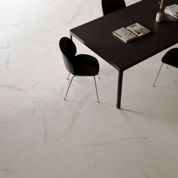 A sleek black table with books sits on a smooth, white marble-tiled floor. Surrounding it are modern black chairs with curved ba