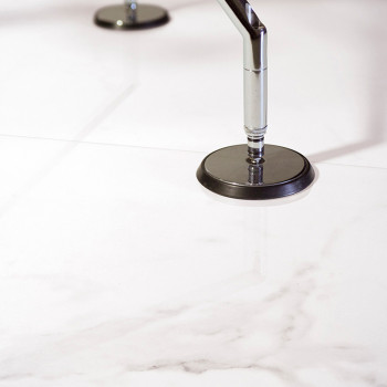 A smooth, white marble tile reflects two metal stoppers securing it to the shiny surface, conveying a sleek, modern design.