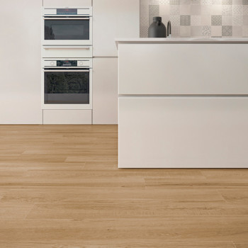 La habitación cuenta con pisos de madera clara que se extienden hacia una cocina moderna con gabinetes blancos. Dos hornos apila